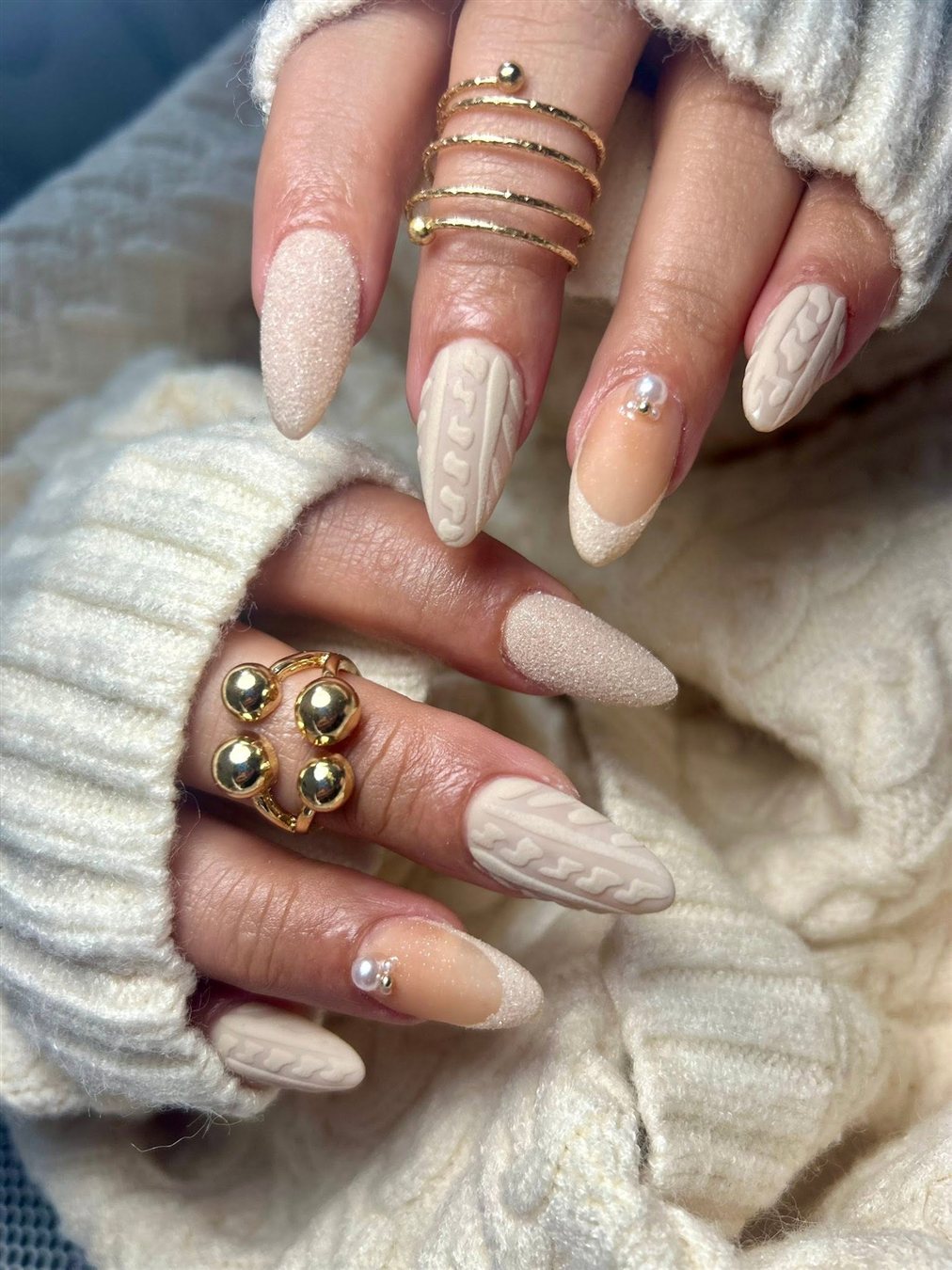 Uñas almendra en tonos crema con textura tejida y perlas